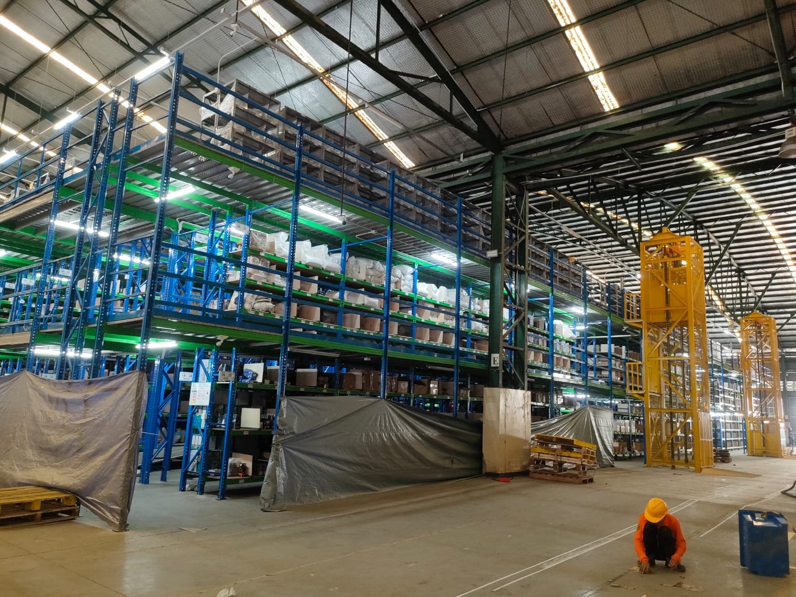 Rak gudang FMCG dengan produk dibungkus plastik wrap di tiap level