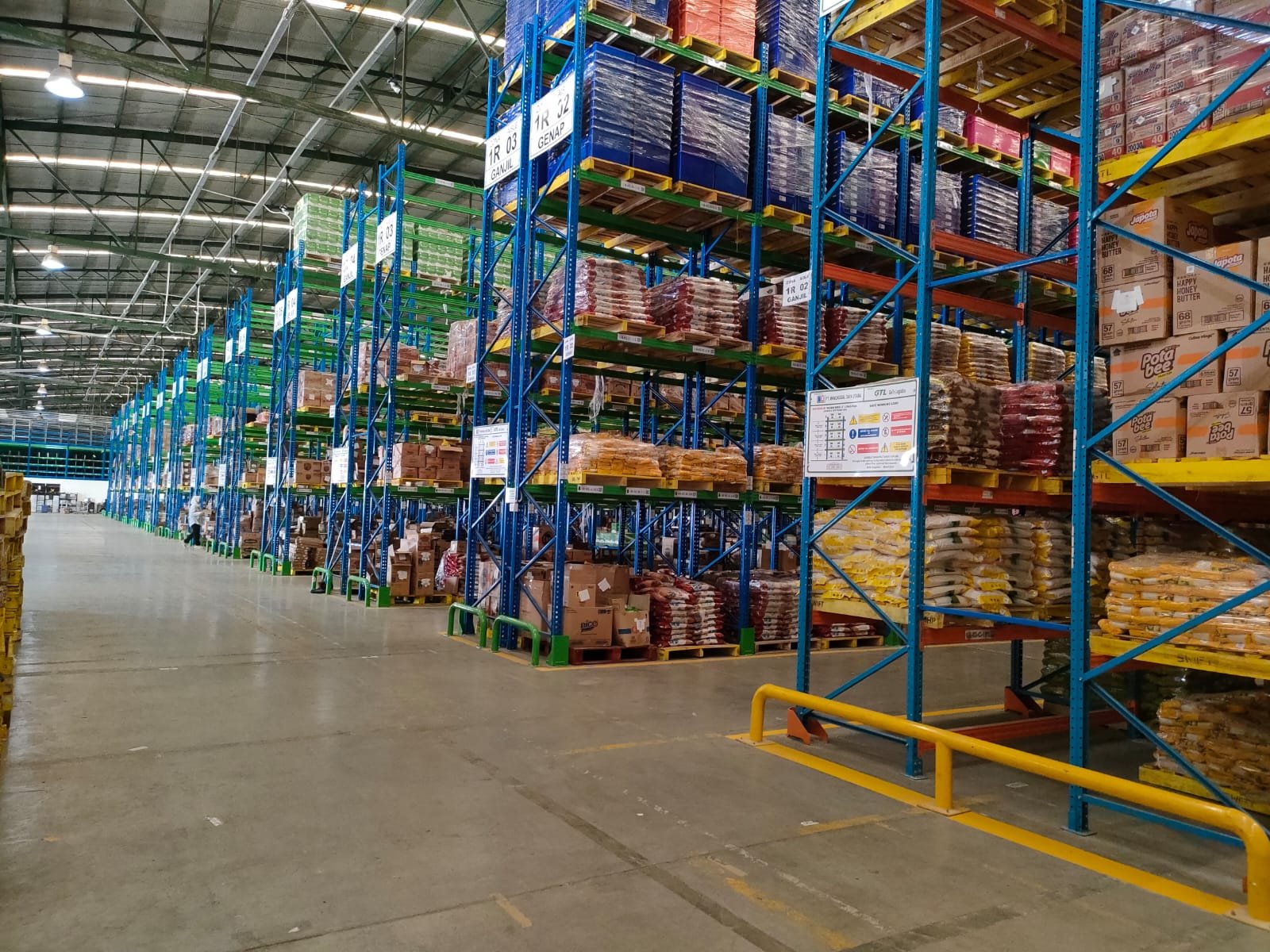 Rak gudang FMCG dengan tumpukan pallet campuran produk makanan dan minuman