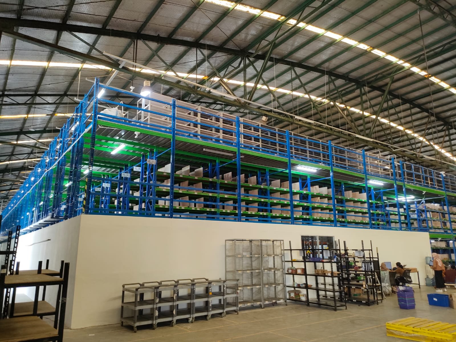 Lorong rak gudang FMCG dengan pallet kayu di lantai